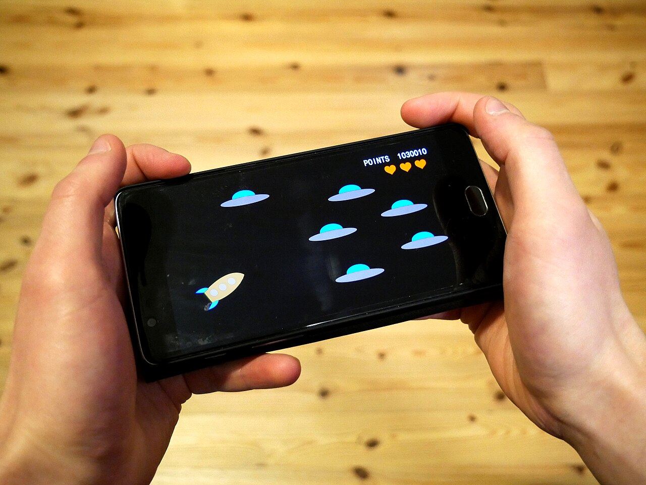 Hands holding a smartphone with a video game on its screen